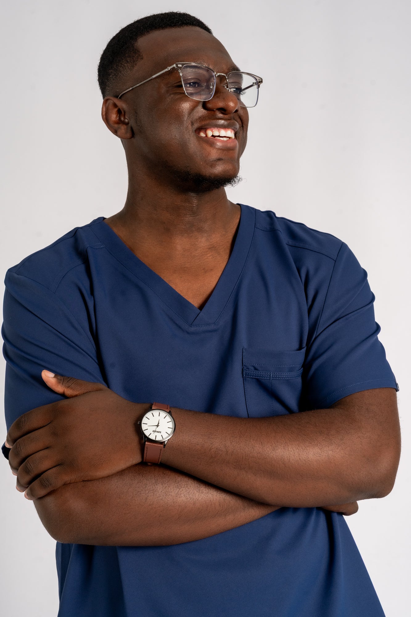 Man wearing a blue scrubs and glasses with a watch on a white background